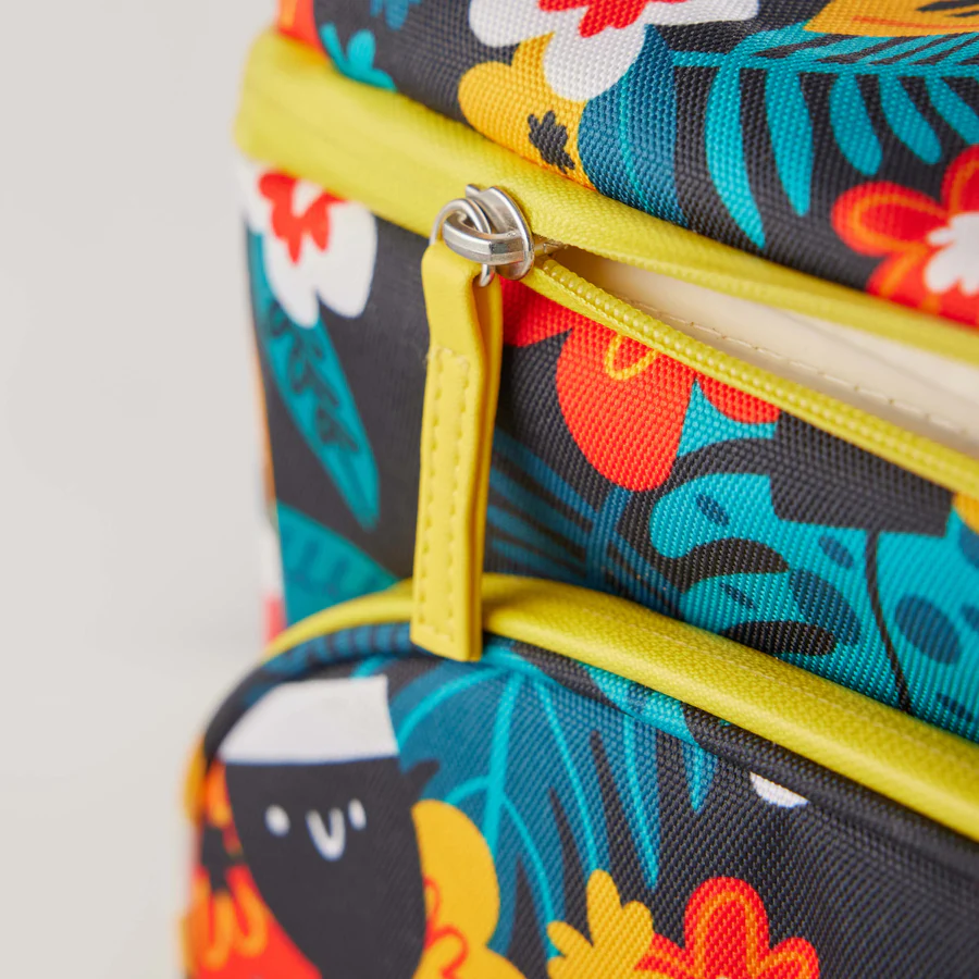 Close-up of the Guinness x Fatti Burke Hawaiian Cooler Bag from Guinness Webstore UK, featuring a colorful floral and leaf pattern, lime green zippers, and a small Fatti Burke character in the bottom left corner.