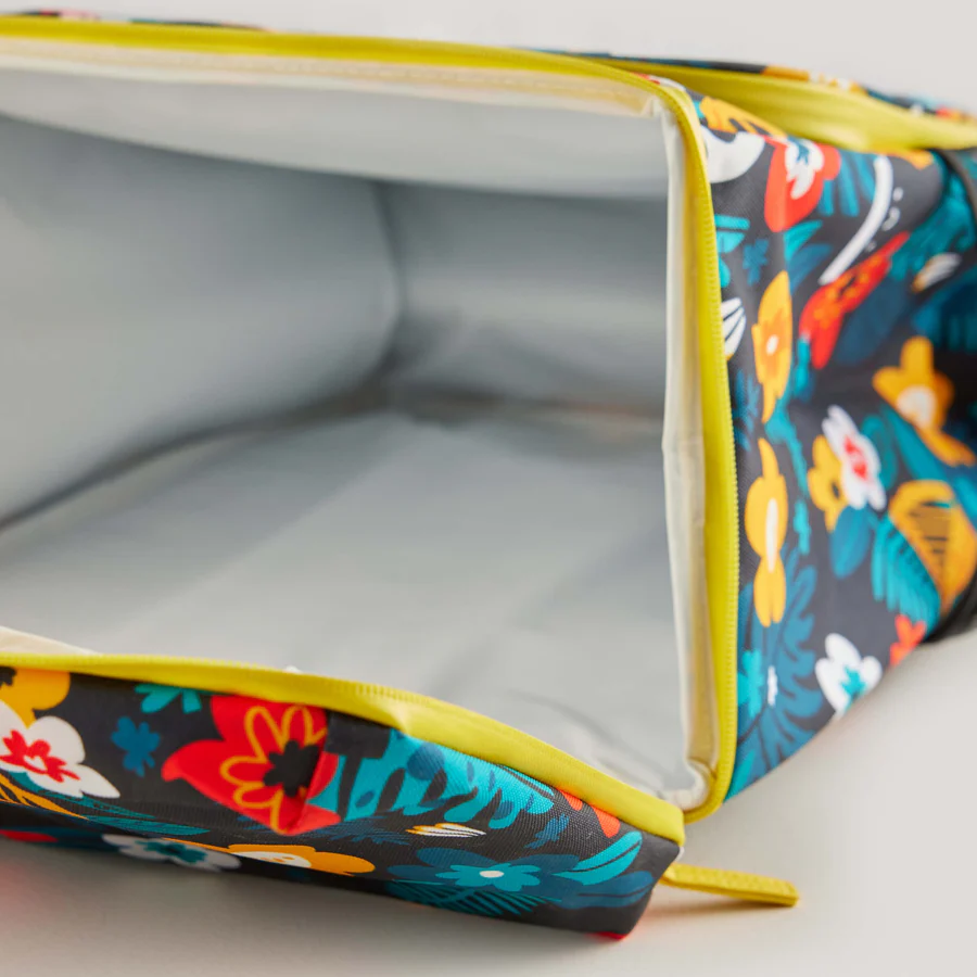 The Guinness x Fatti Burke Hawaiian Cooler Bag from Guinness Webstore UK, with a vibrant floral design and yellow zipper, displays its empty silver insulated interior featuring unique Fatti Burke illustrations.
